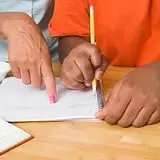 A person is writing on paper with a pencil.