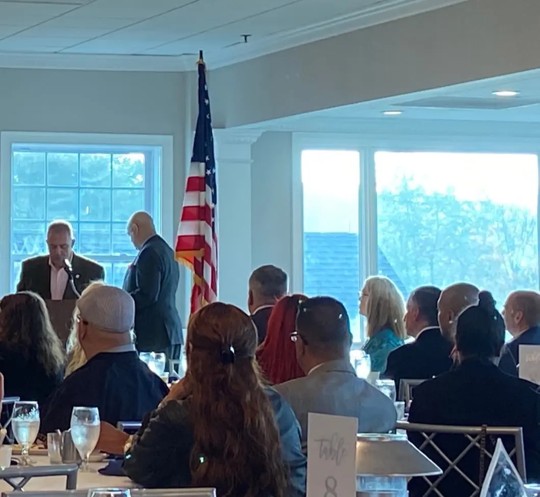 Group of people seated at a table with an American flag.
