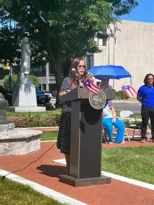 A woman is speaking at an outdoor event.