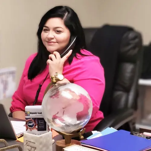 A woman sitting at her desk talking on the phone.