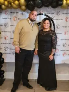 A couple posing in front of a fitness fury backdrop.
