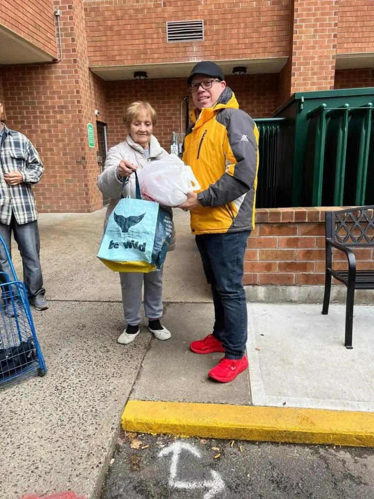 Two people standing outside with groceries.
