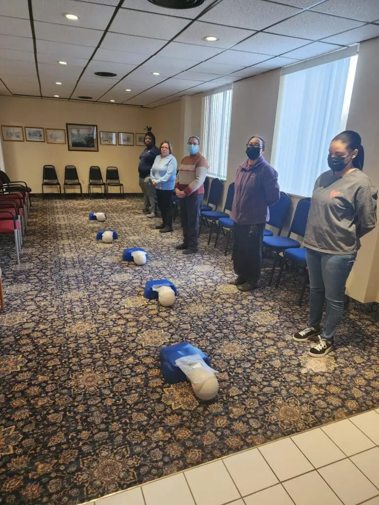A group of people standing in front of cpr dummies.