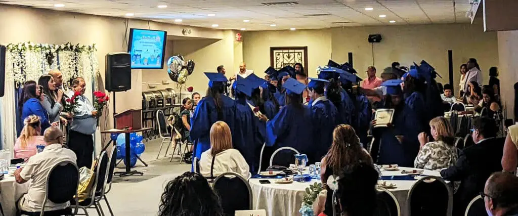 A group of graduates in blue caps and gowns.