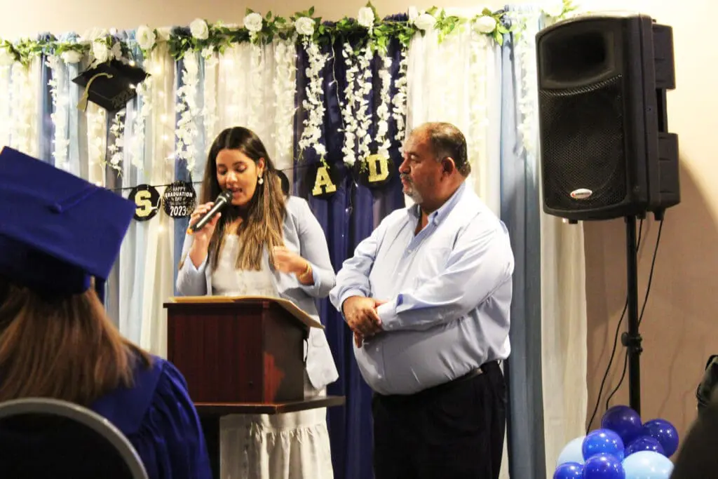 A woman standing at the podium with an older man.
