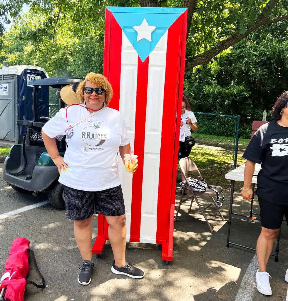 A woman standing next to a large puerto rican flag.