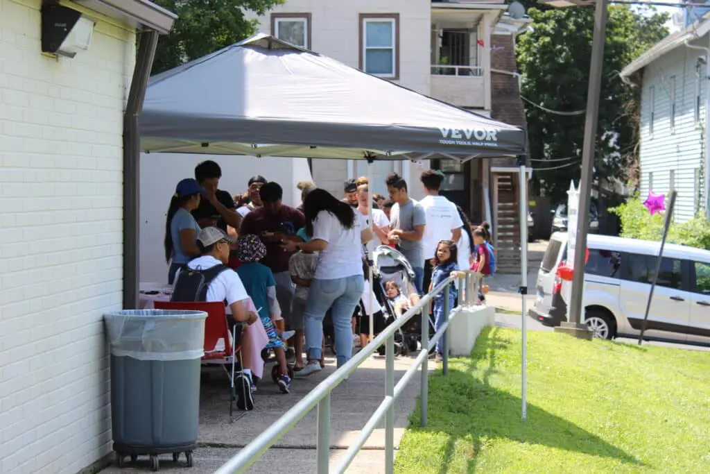A group of people standing around an outdoor tent.