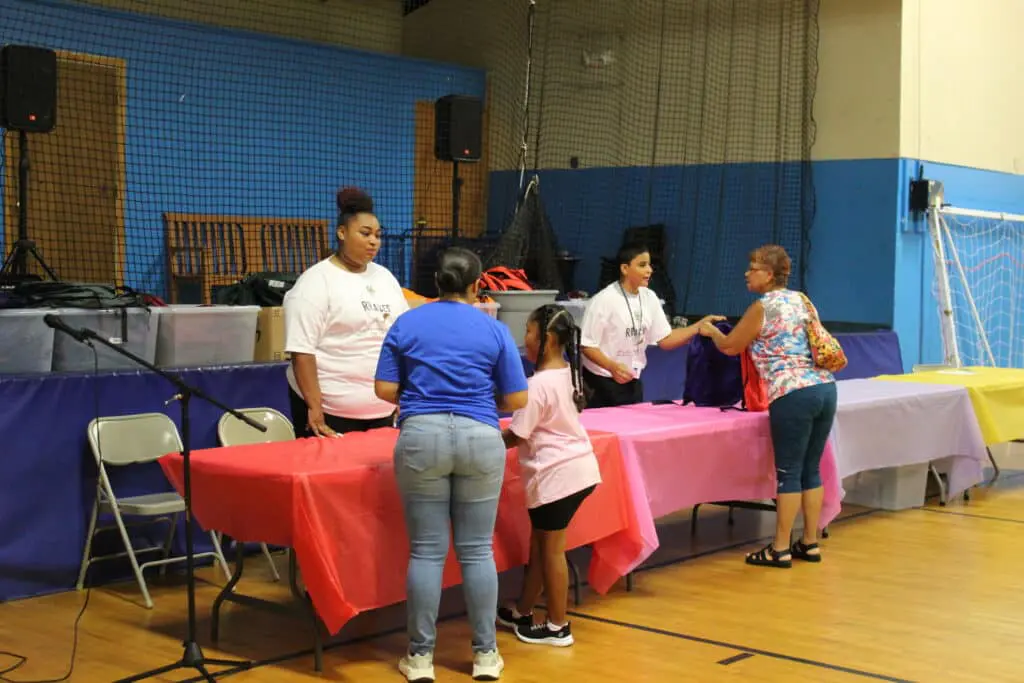A group of people standing around tables in a room.