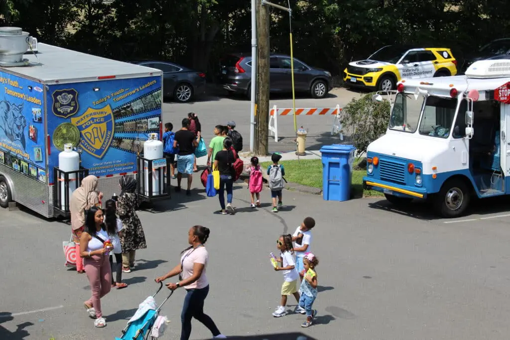 A group of people walking around in front of a food truck.