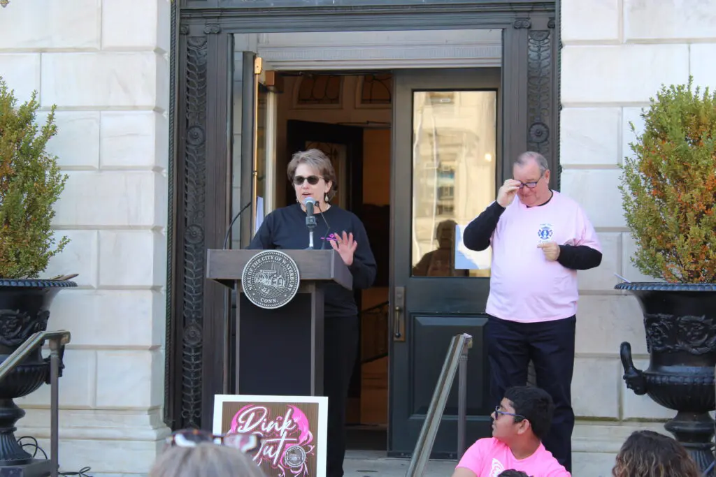 A woman standing at the podium in front of people.