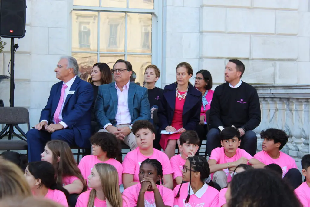 A group of people sitting on steps with pink shirts.
