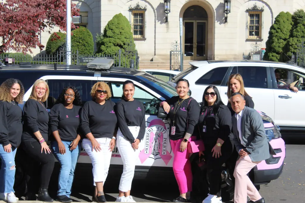 A group of people standing next to a car.