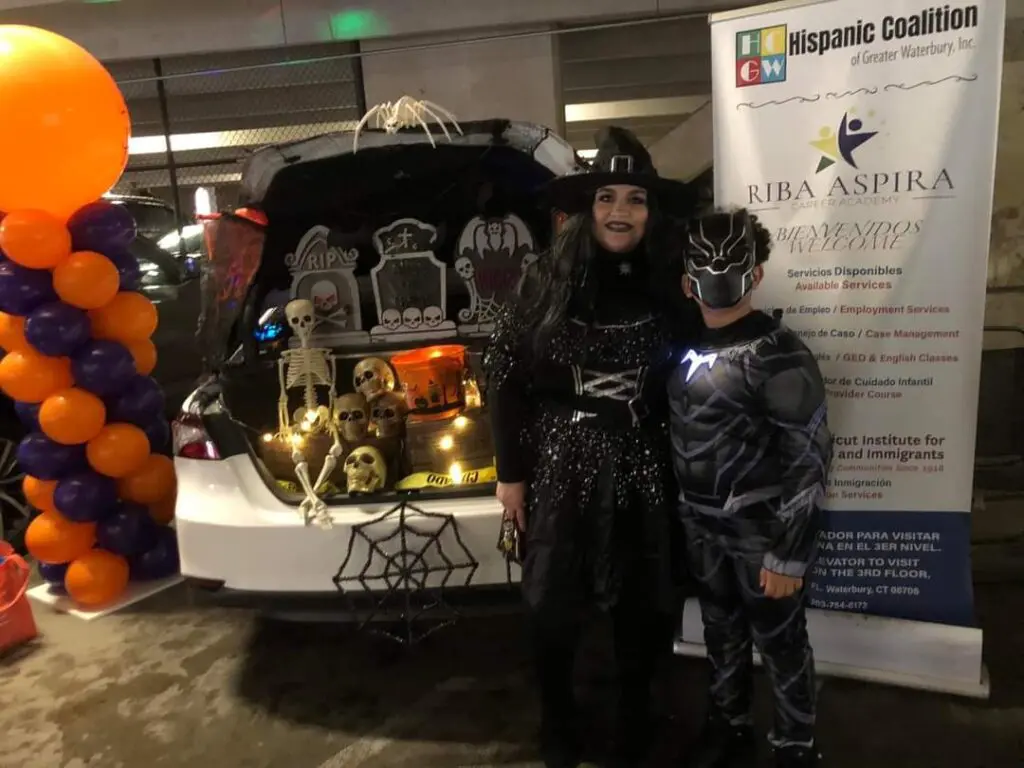 Two people dressed up in costumes next to a trunk.
