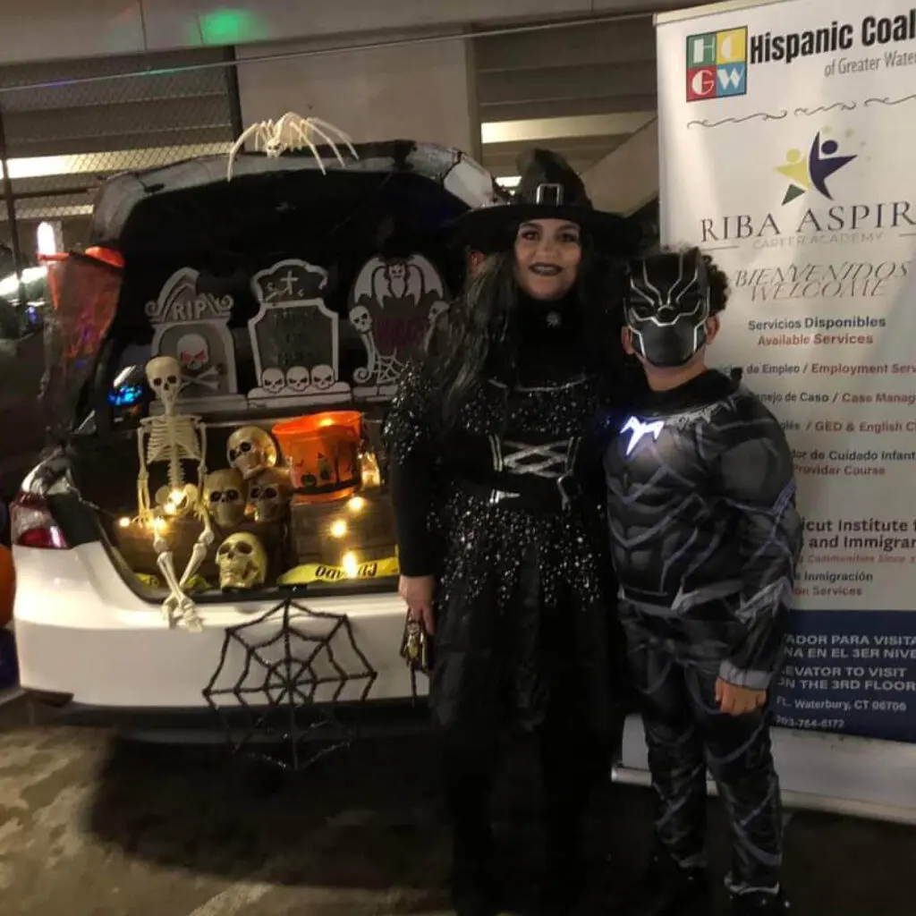 Two people in costumes standing next to a trunk.
