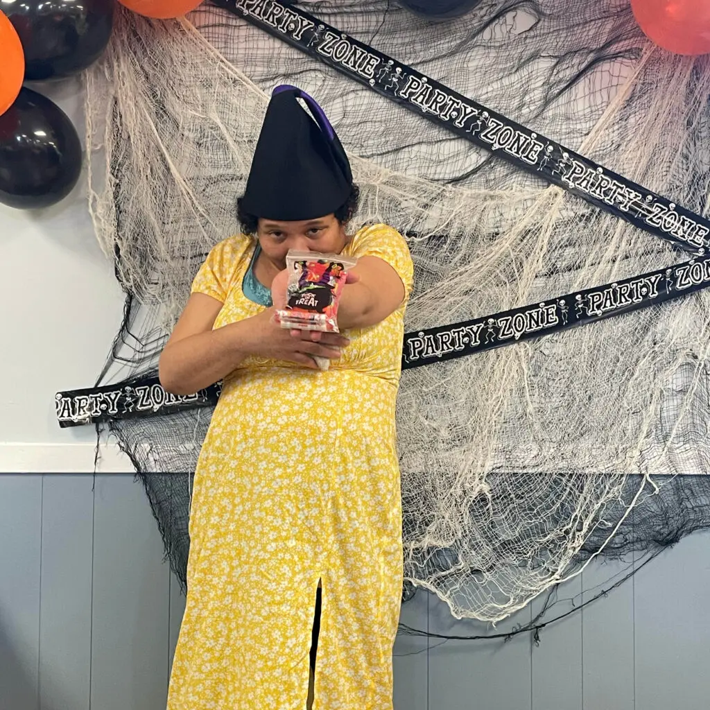 A woman in yellow dress taking a photo with her phone.
