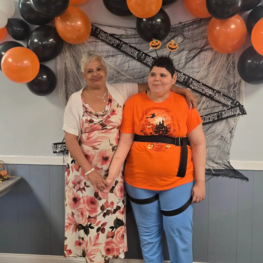 Two people standing next to each other in front of a wall with balloons.