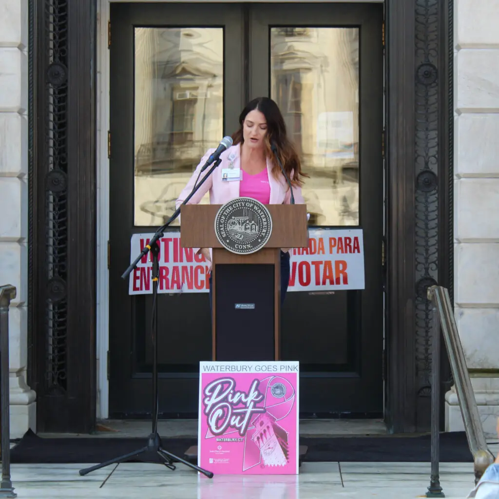 A woman standing at the podium in front of a building.