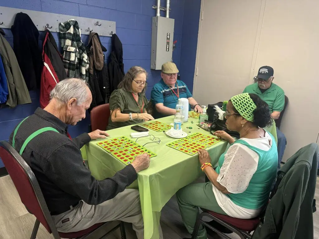 A group of people sitting at a table playing scrabble.