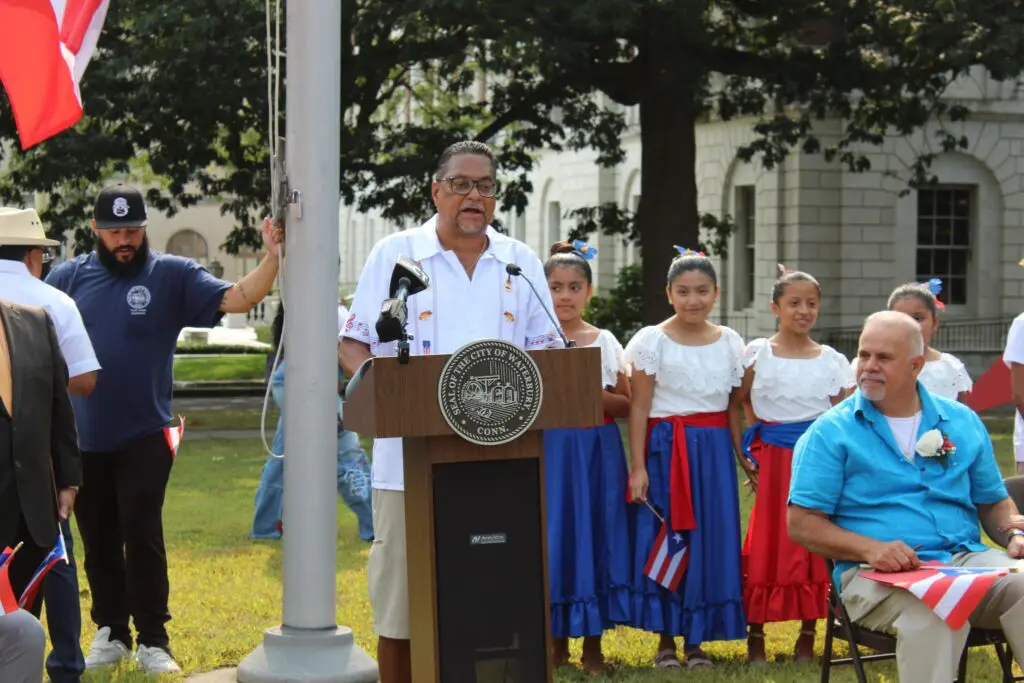 Man speaking at outdoor event with children.