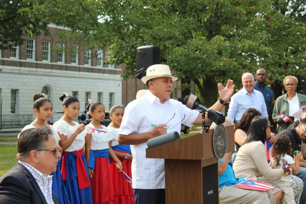 Man speaking at outdoor event with audience.