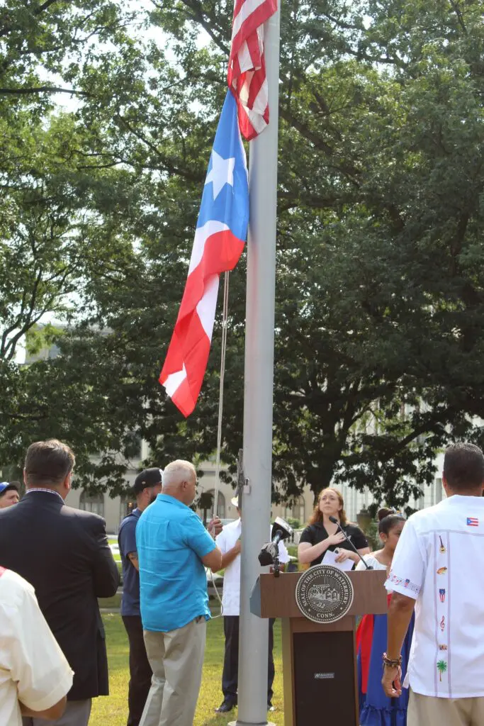 Flag-raising ceremony with people gathered outdoors.