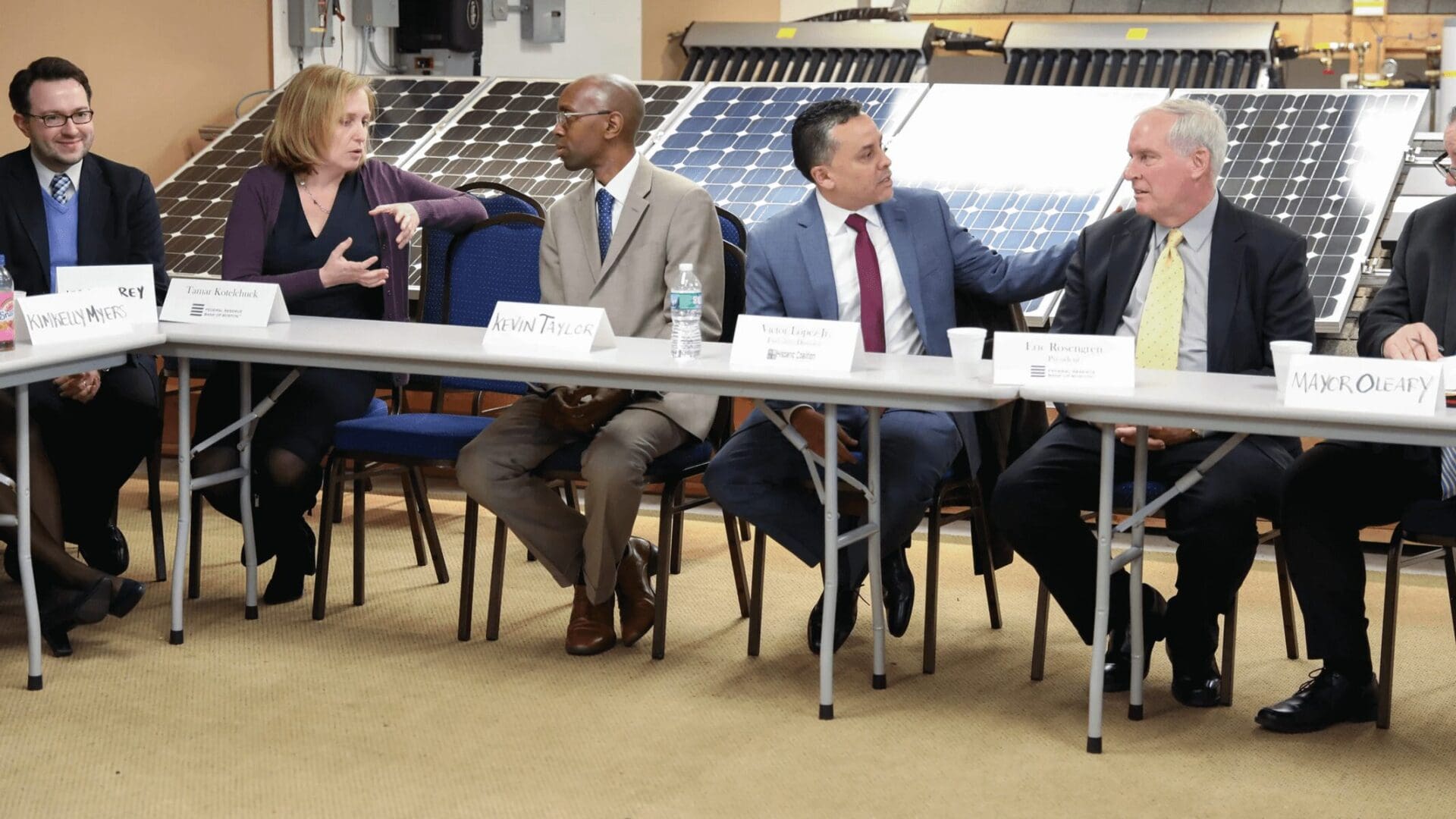 A group of people sitting at tables with chairs.