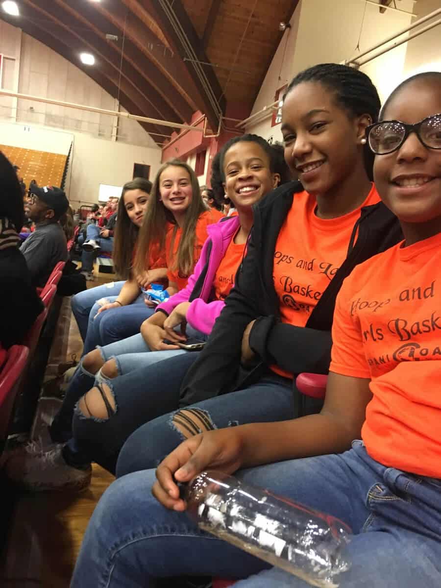 A group of girls sitting in front of each other.