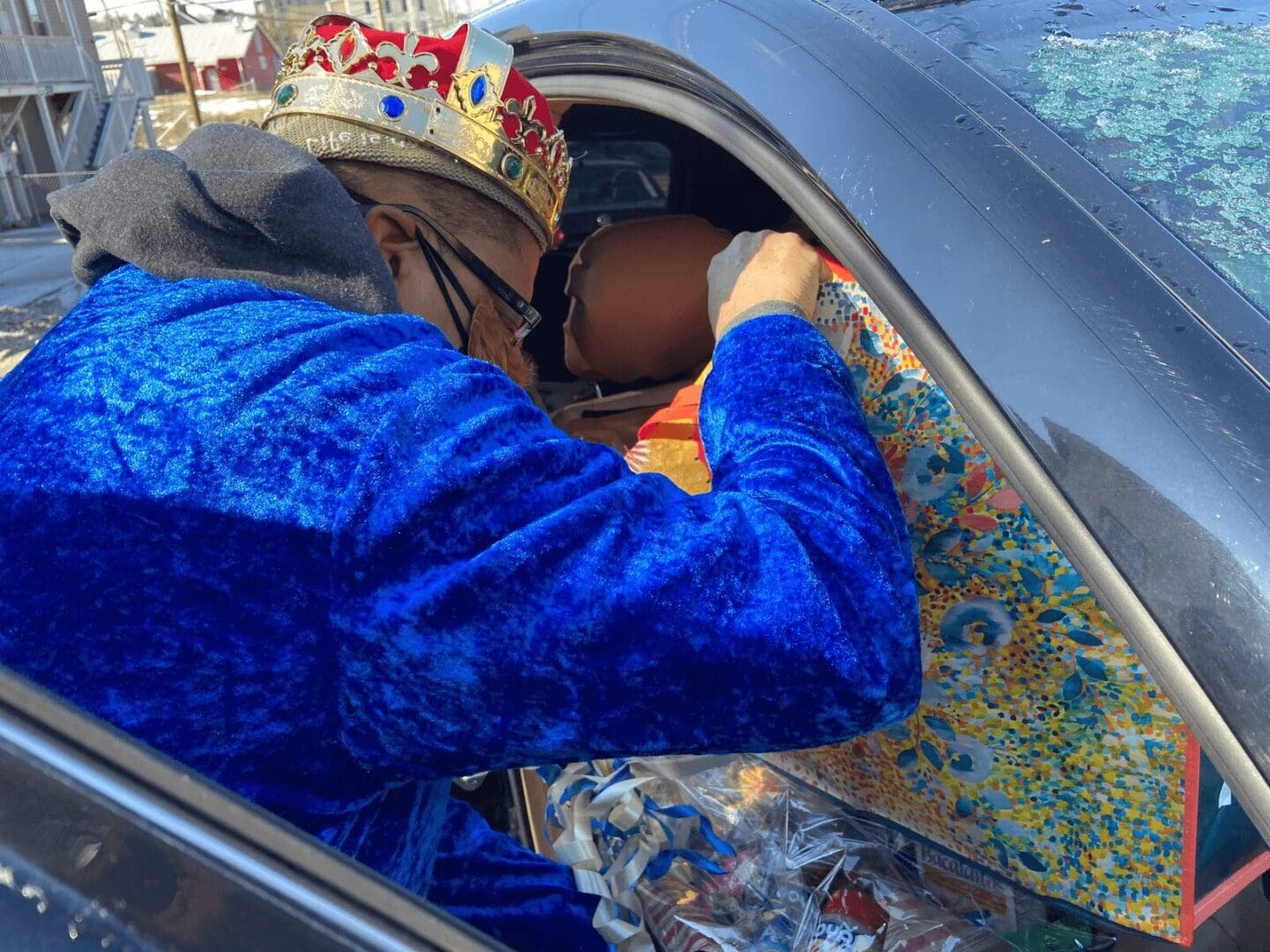 Man in blue robe and crown in car.