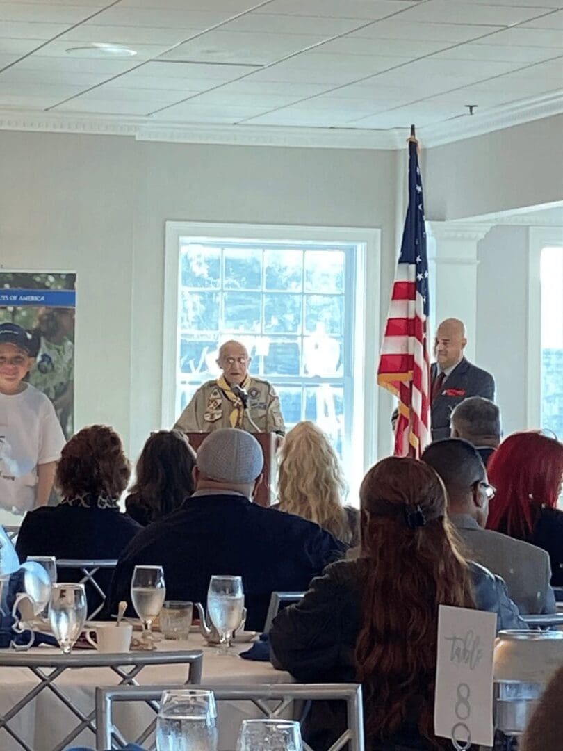 Man speaking at a ceremony with guests.