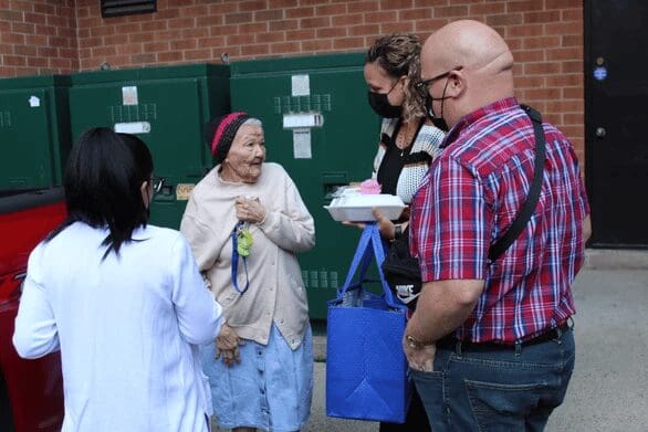 Four people stand by green containers.