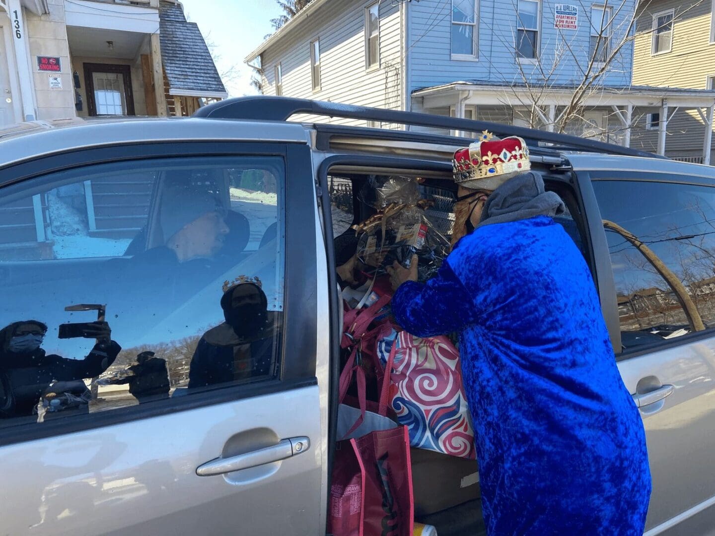 Person in blue robe loading gifts into car.