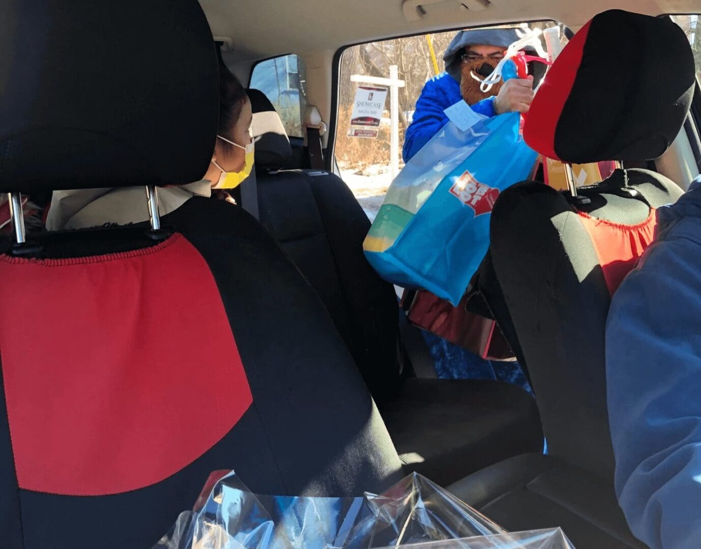 A woman in the back of a car with some bags