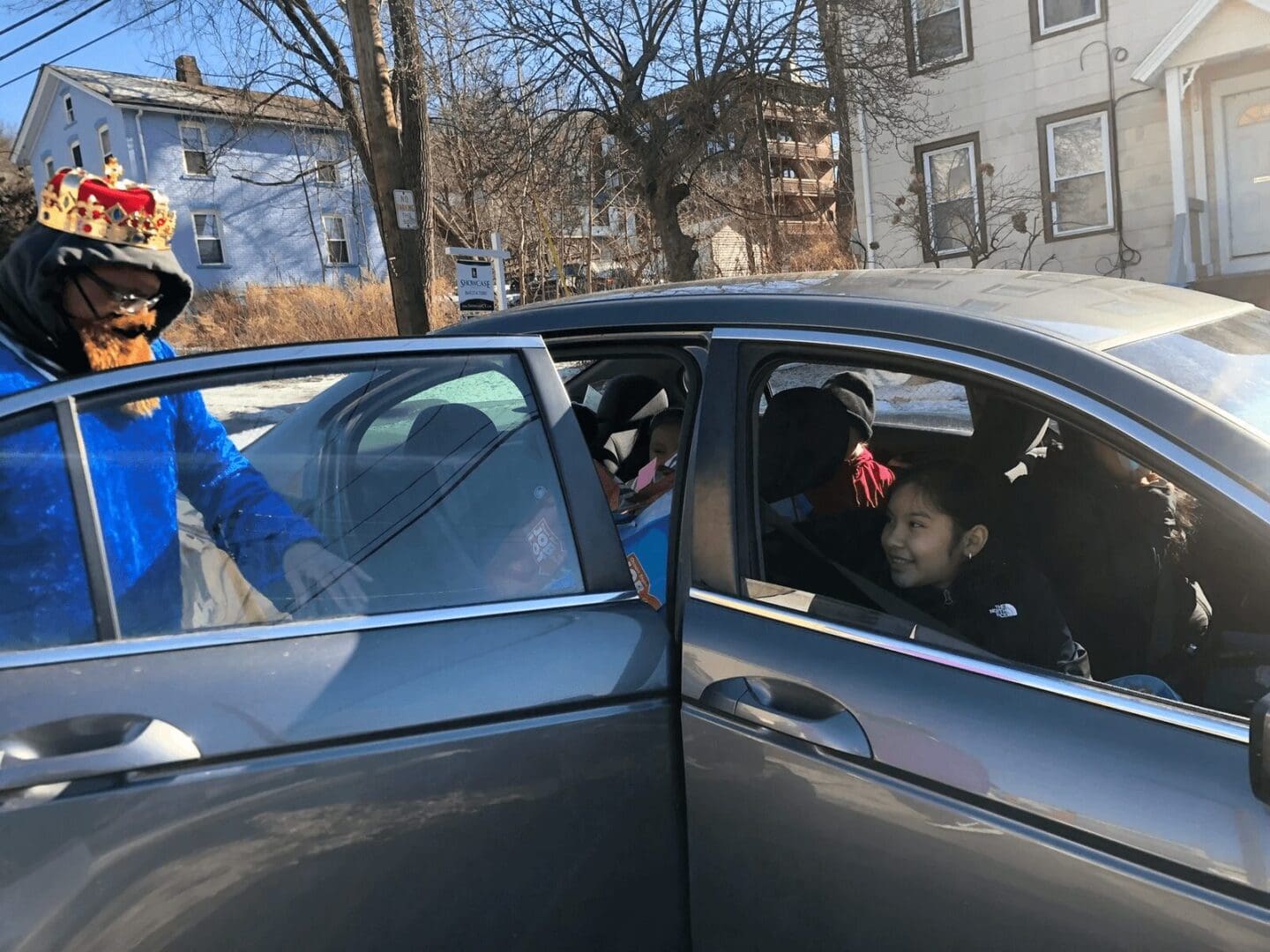 A man with a crown getting into a car.