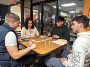 A group of people sitting around a table playing dominoes.