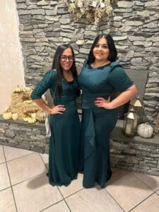 Two women in green dresses by a fireplace.