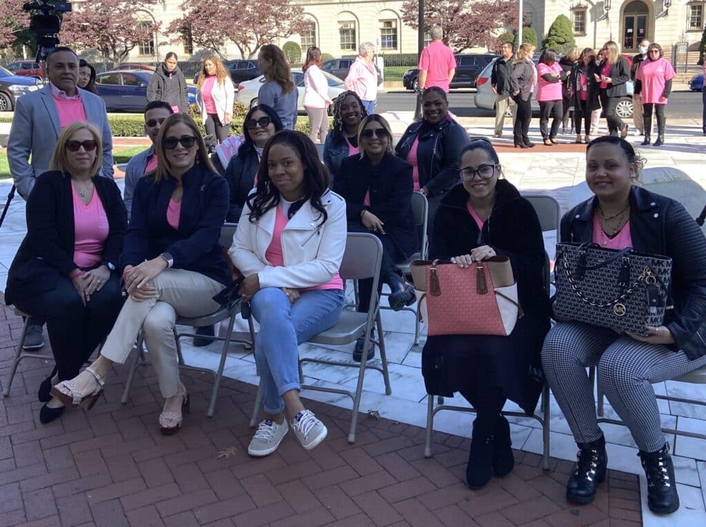 A group of women sitting in chairs on the sidewalk.