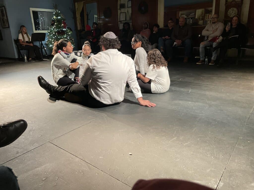 Group of people sitting on a floor.