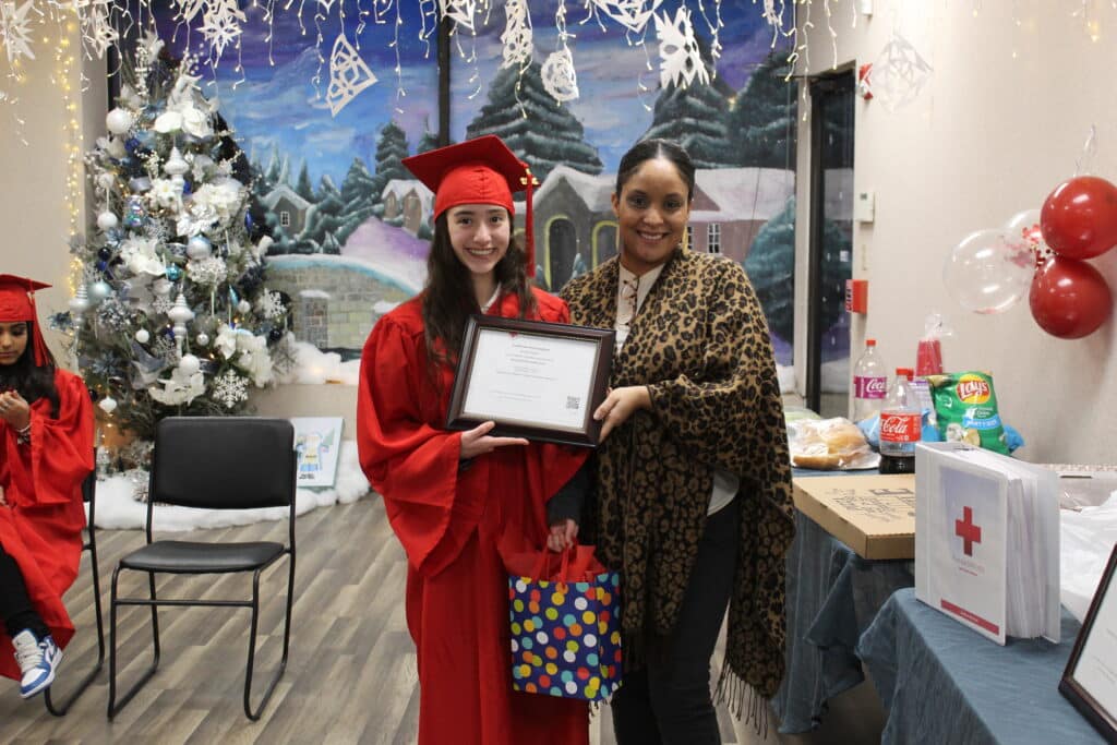 A woman and girl holding a certificate in front of christmas decorations.