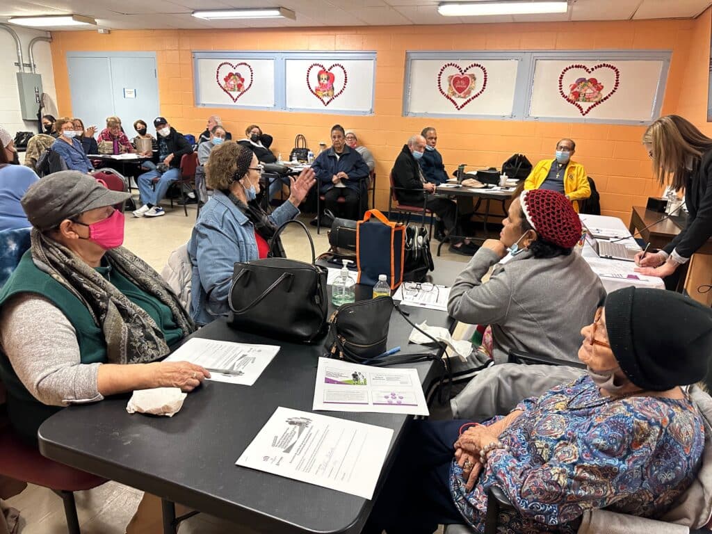 A group of people sitting at tables in front of hearts.