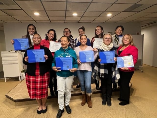 A group of people holding up blue certificates.