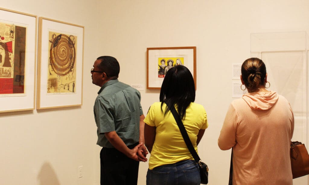 A group of people standing in front of some paintings.