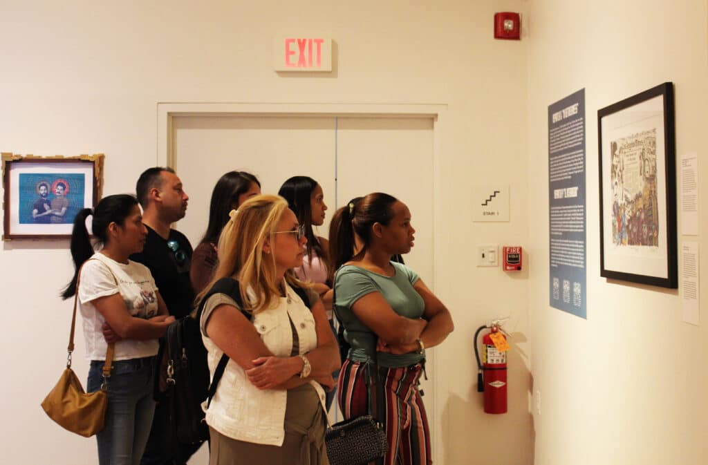 A group of people standing around looking at a wall.