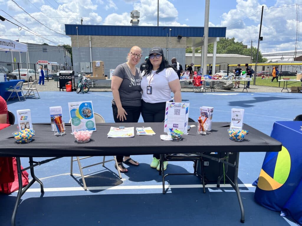 Two women standing next to a table with drinks on it.