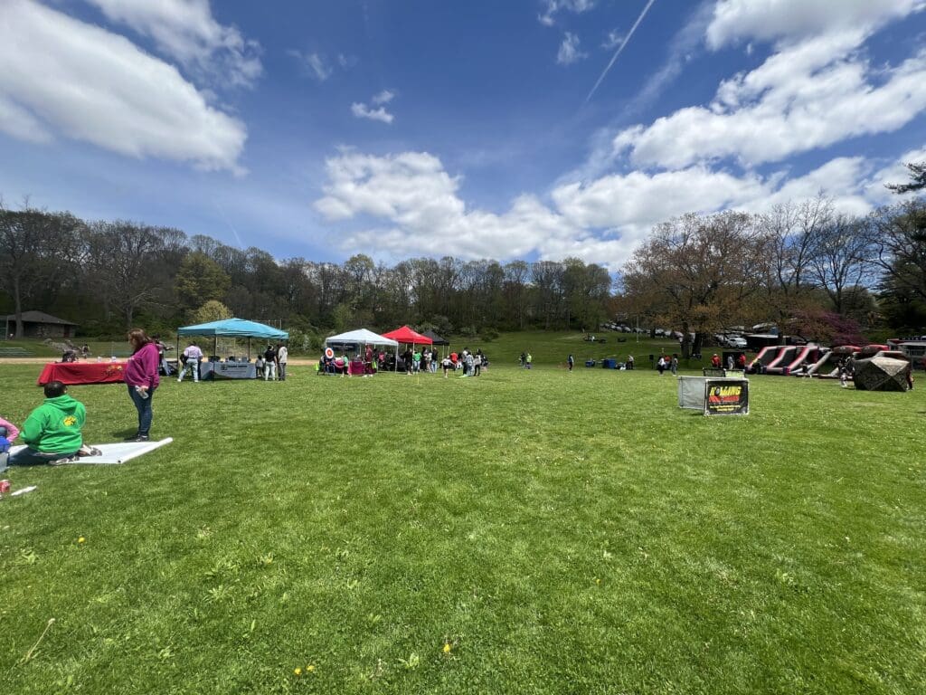 A group of people in the grass with umbrellas.