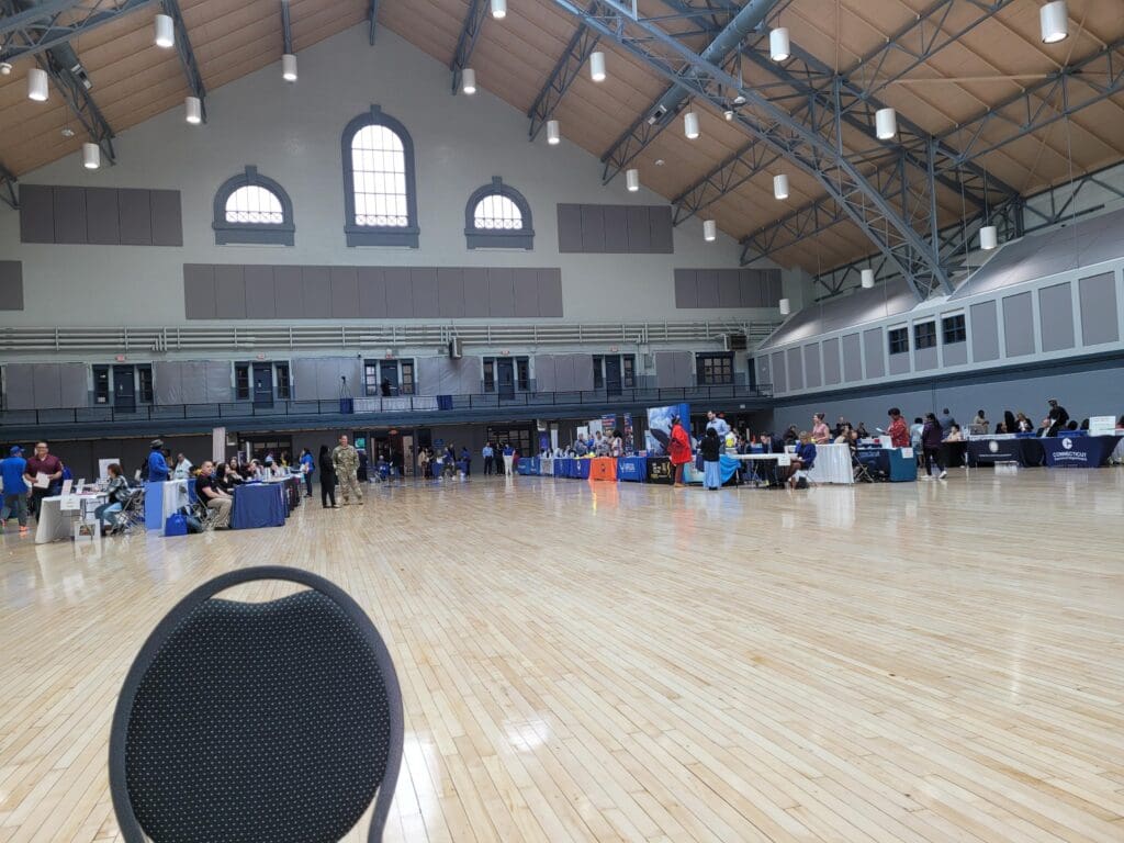 A large gymnasium with people sitting in chairs.