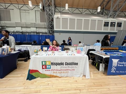 A woman sitting at a table with an event banner.