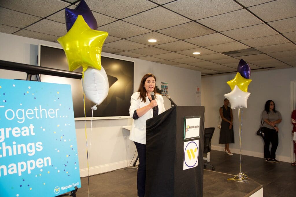 A woman standing at the podium with balloons in front of her.