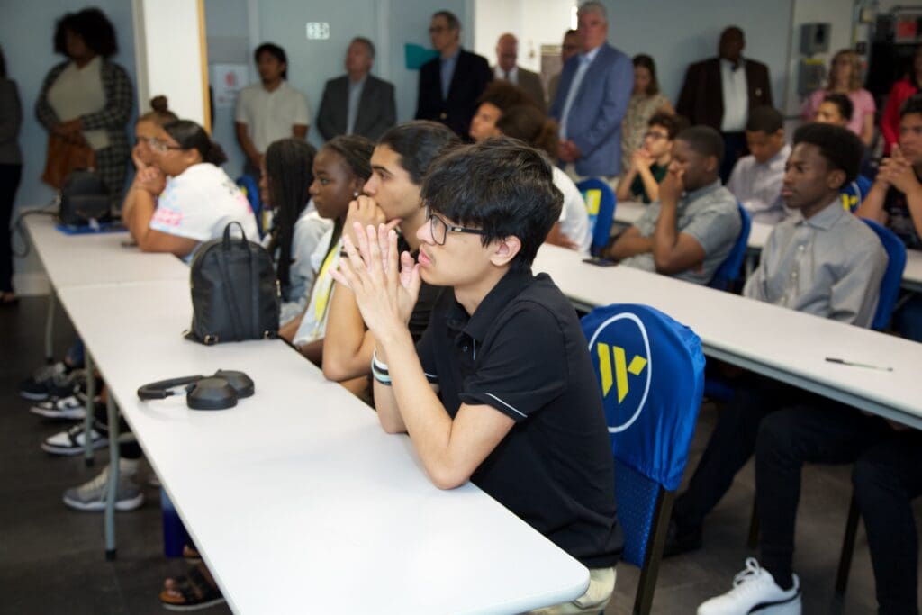 A group of people sitting at tables in front of a crowd.