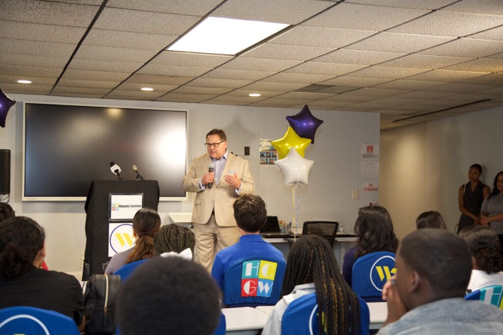 A man in suit and glasses is giving a presentation.