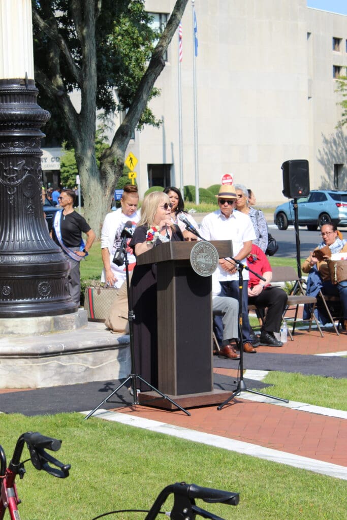 A woman is speaking at an outdoor event.